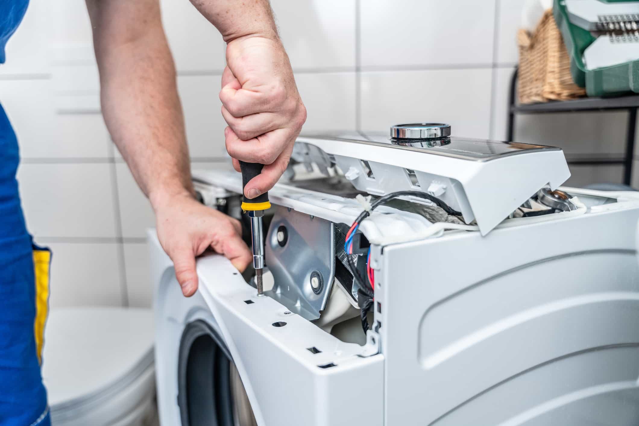 a man is fixing a washing machine with a screwdriver